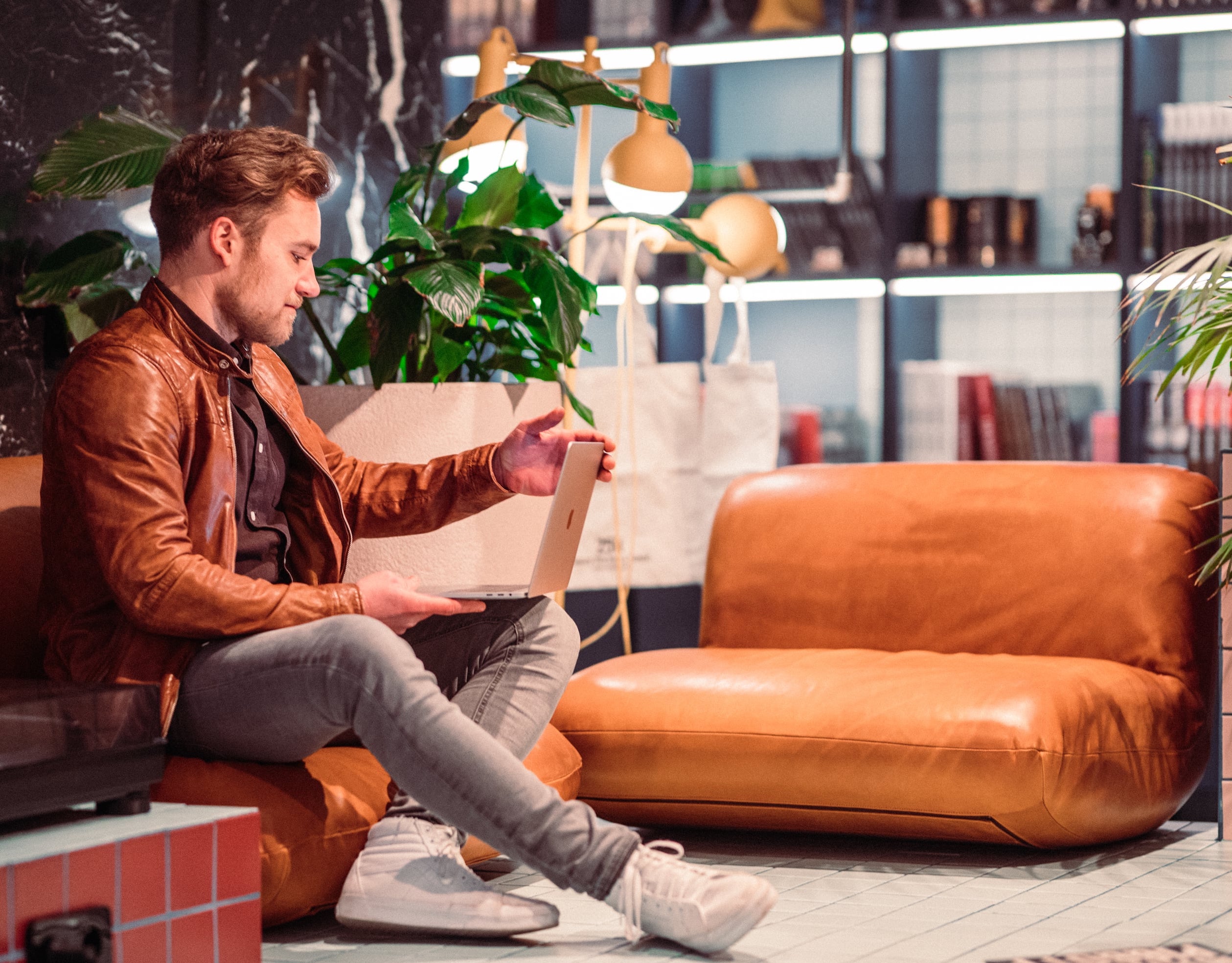 Ein Mann sitzt mit seinem Latop auf einem Sofa in einem Coworking Space