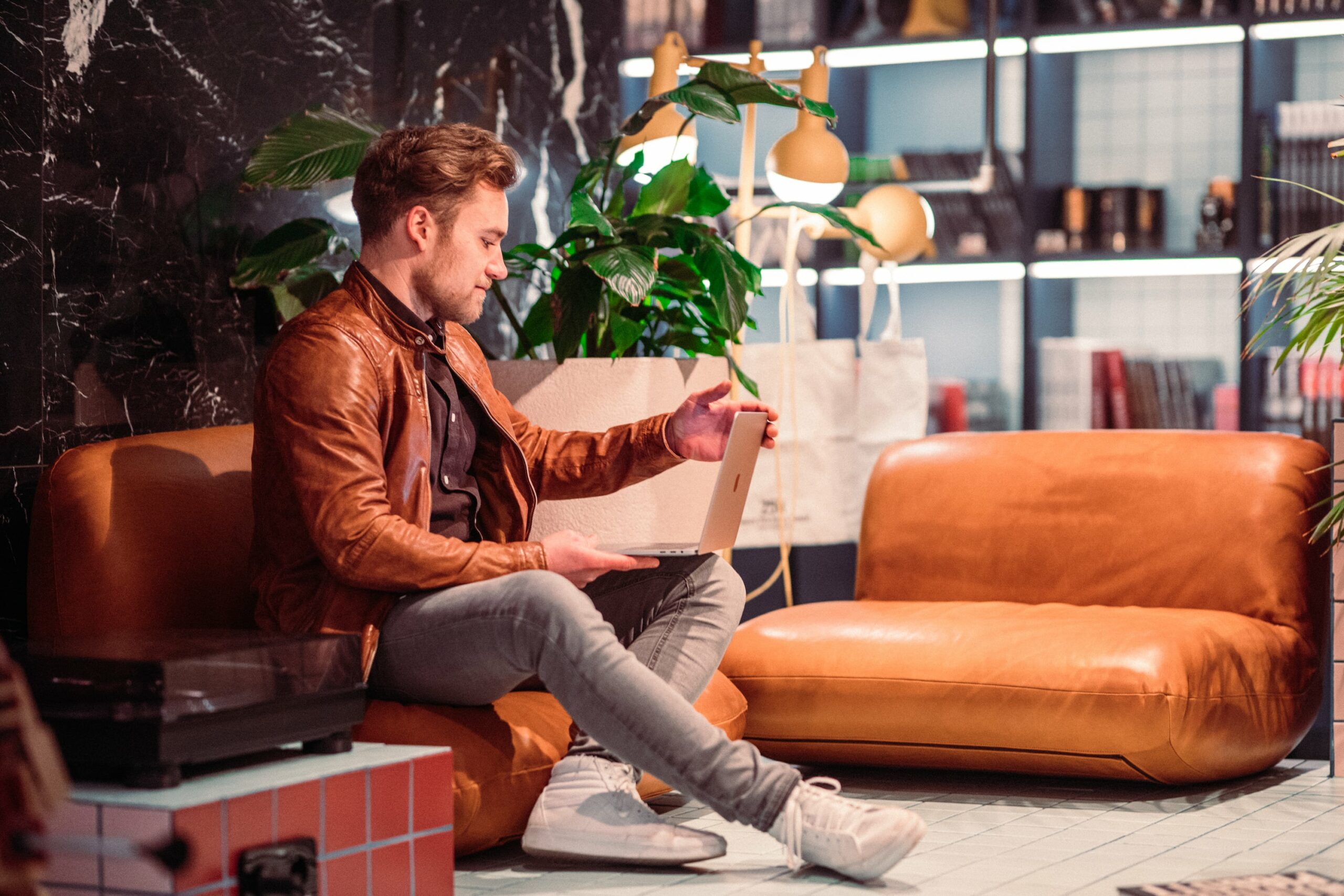 Ein Mann sitzt mit seinem Latop auf einem Sofa in einem Coworking Space